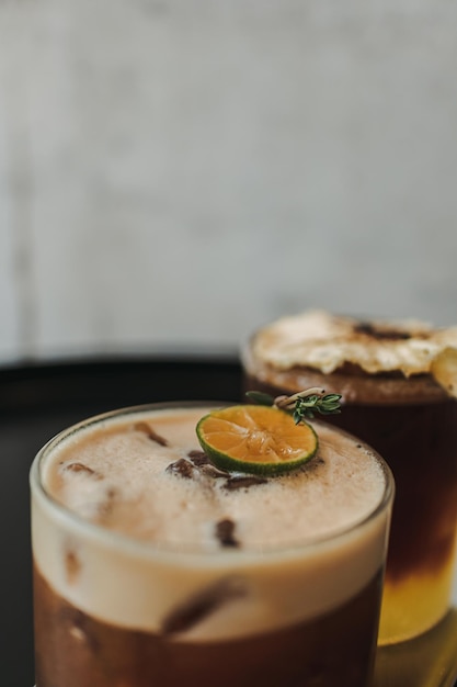 Dos bebidas especiales de café naranja helado servidas en una mesa negra en el café