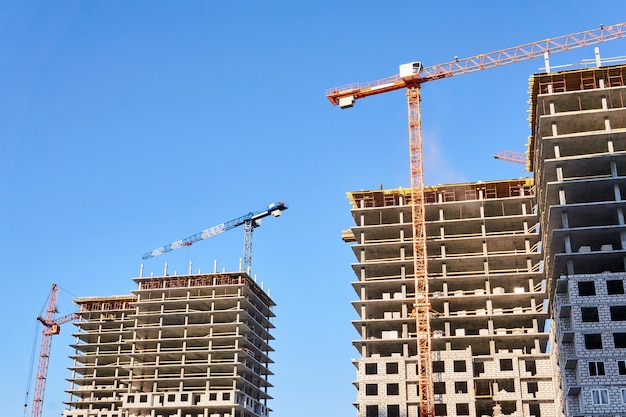 Dos bloques de pisos de varios pisos en construcción con grúas torre contra el cielo