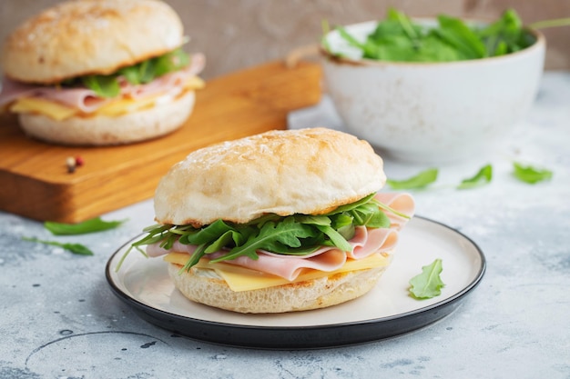 Dos bocadillos caseros con jamón, queso y rúcula sobre una mesa de hormigón