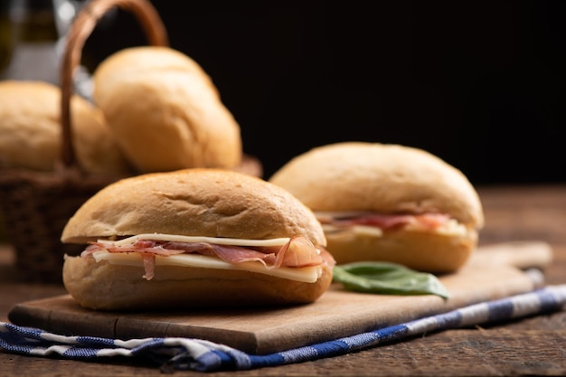 Dos bocadillos con jamón y queso sobre mesa de madera