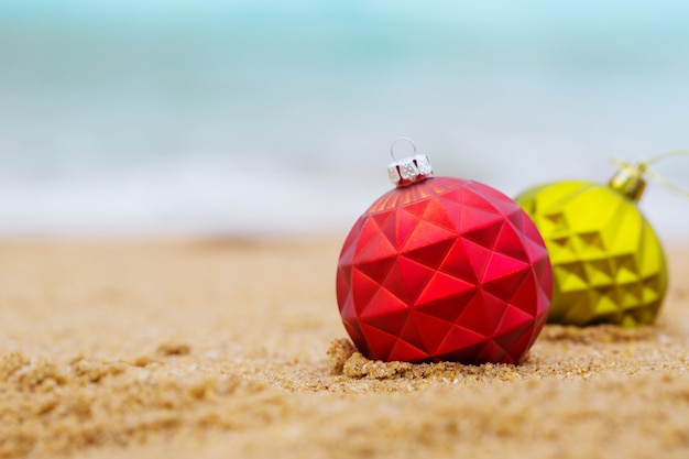 Dos bolas de Navidad en la orilla arenosa del océano