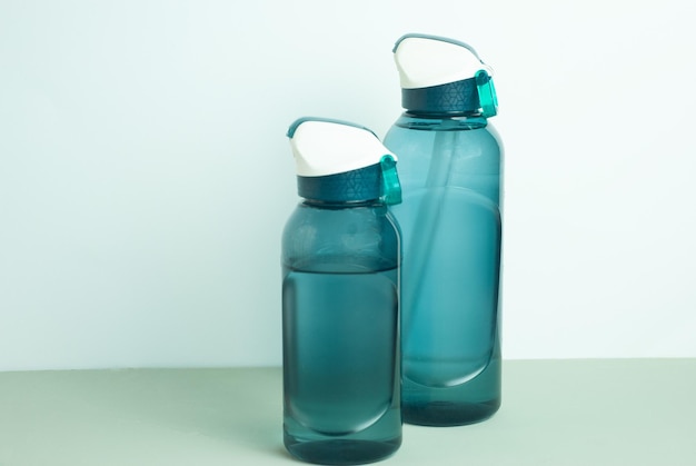 Dos botellas de agua azules con tapas verdes se sientan en una mesa.