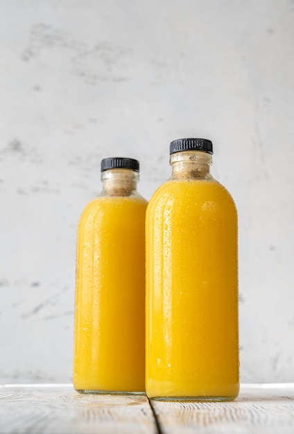 Dos botellas de jugo de naranja en el fondo de madera