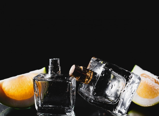 Dos botellas de perfumes con cítricos sobre negro