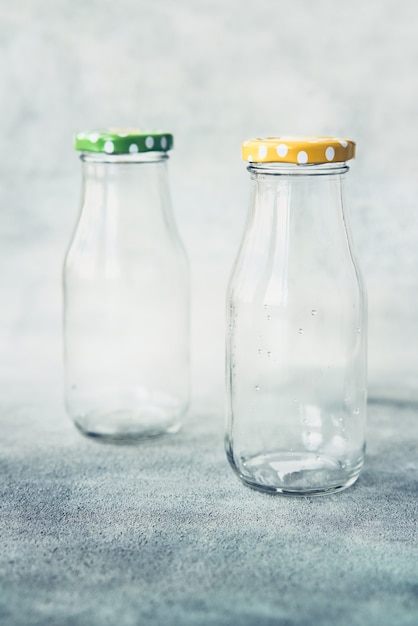 Dos botellas de vidrio vacías con tapa sobre fondo gris espacio de copia