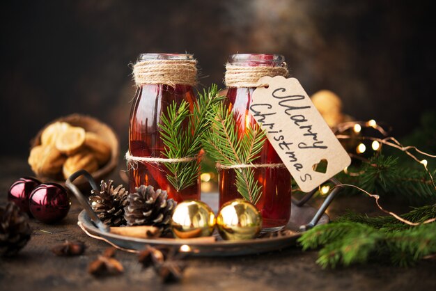 Dos botellas de vino caliente caliente de Navidad con especias en una pared de madera.