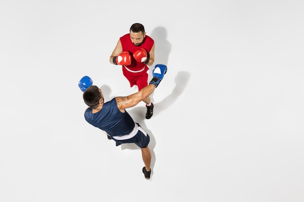 Dos boxeadores profesionales de boxeo aislado sobre fondo blanco de estudio, acción, vista superior. Par de atletas caucásicos musculosos en forma peleando. Concepto de deporte, competición, emoción y emociones humanas.