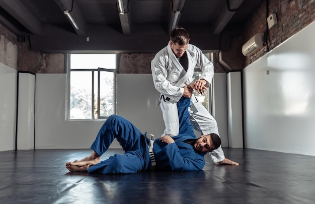 Dos boxeadores que se enfrentan a un compañero en kimono se entrenan en una sala de deportes