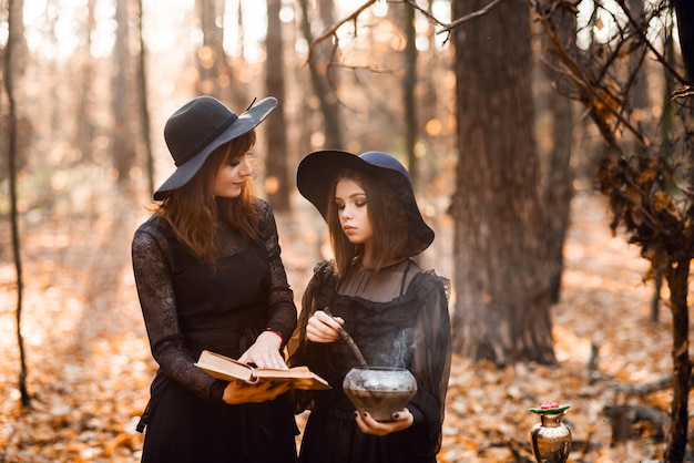 Dos brujas en el bosque de otoño. Madre e hija preparan una poción.