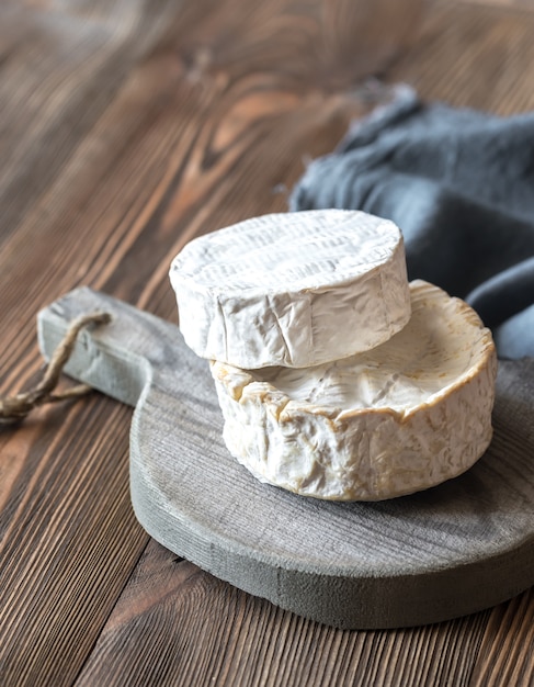 Dos cabezas de camembert en la tabla de madera