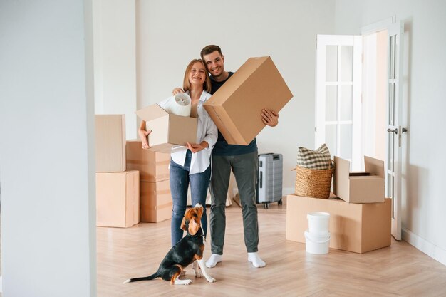 Foto dos cajas en las manos una joven pareja con perro se mudan a una nueva casa