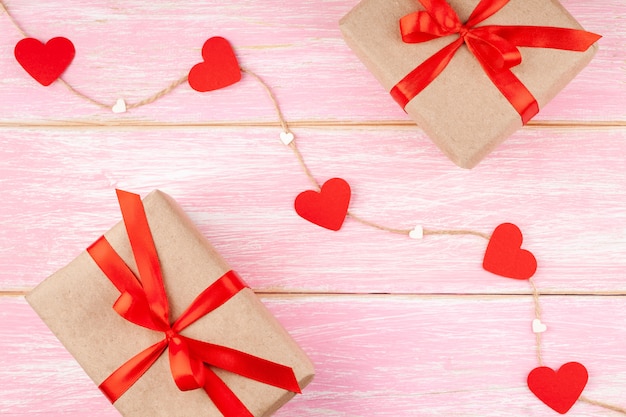 Dos cajas de regalo con lazo de cinta roja y corazones de papel