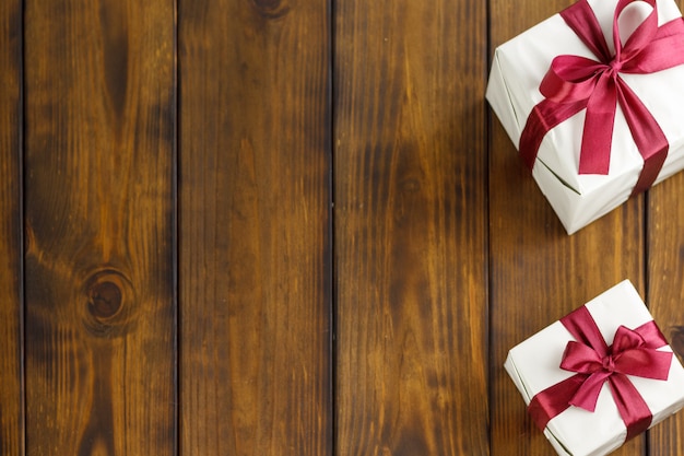 Dos cajas de regalo en una mesa de madera marrón. Cintas rojas en las cajas.