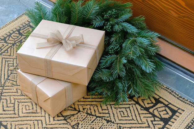 Dos cajas de regalos apiladas en una alfombra de bienvenida con una corona de pino