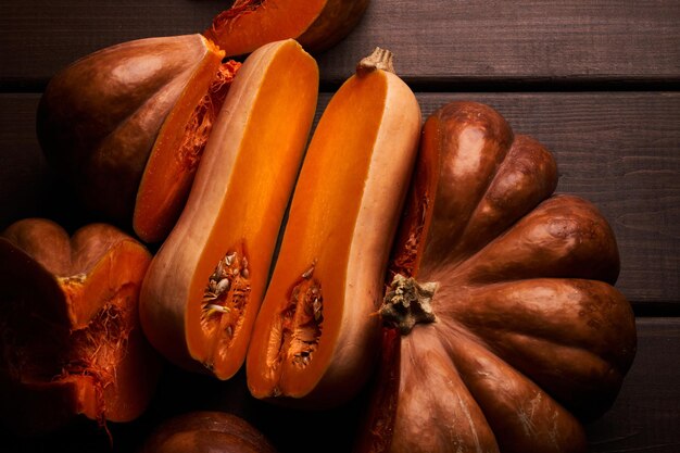 Dos calabazas naranjas maduras en rodajas diferentes closeup fondo de madera