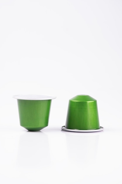 dos cápsulas de café espresso verde de la cafetera automática aisladas sobre un fondo blanco