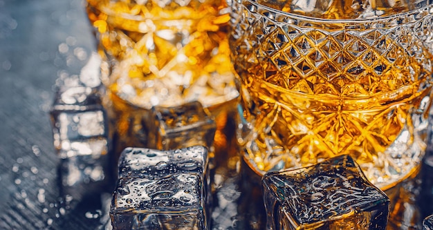 Dos caros vasos de whisky con hielo en una bandeja de piedra negra