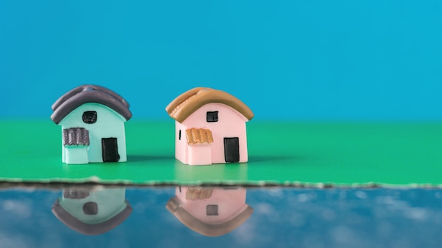 Dos casas de cerámica en miniatura sobre superficie azul y verde