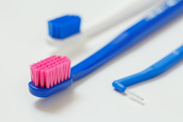 Dos cepillos de dientes y un cepillo interdental sobre el fondo blanco. Poca profundidad de campo.