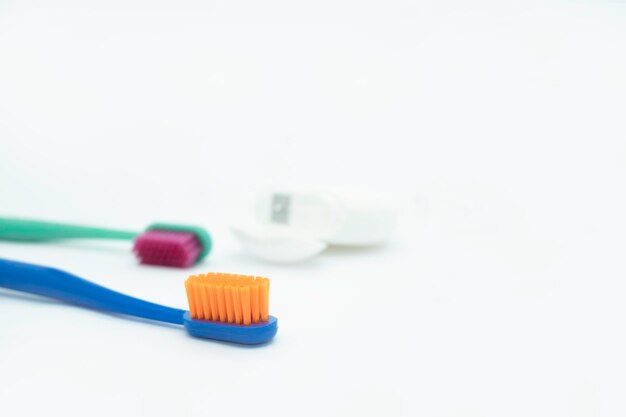 Dos cepillos de dientes de colores con hilo dental de cerdas de color naranja brillante y rojo sobre un fondo blanco.