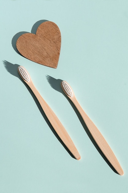 Dos cepillos de dientes de madera de bambú ecológicos y un corazón de madera sobre un fondo azul Ver ht