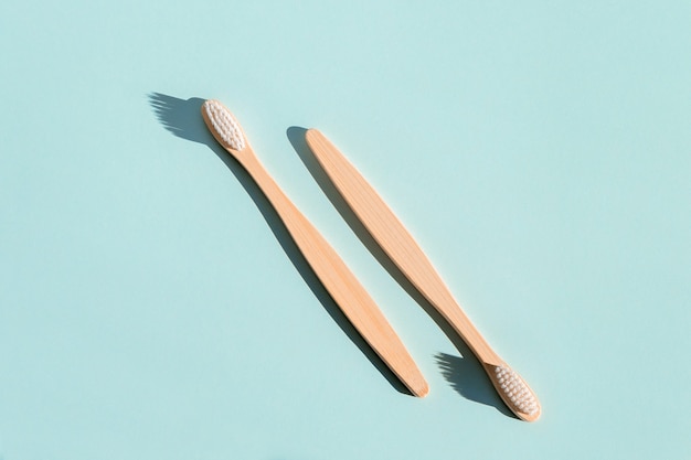 Dos cepillos de dientes de madera de bambú ecológicos sobre un fondo azul claro Luz dura Vista desde arriba