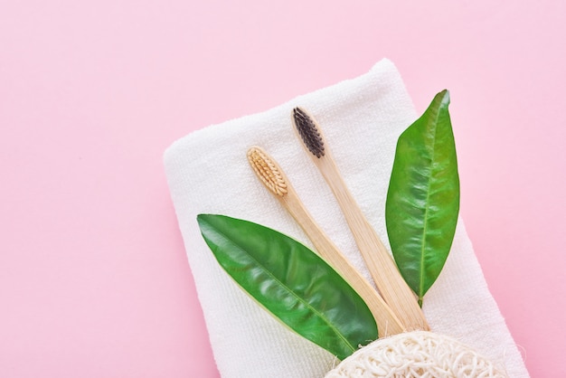 Dos cepillos de dientes respetuosos con el medio ambiente de bambú de madera, toalla y toallita en un rosa