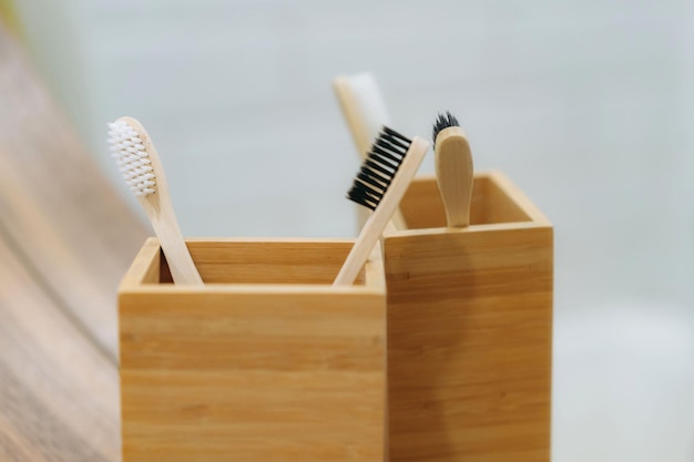 Dos cepillos de dientes en soporte de bambú que se reflejan en el espejo del baño