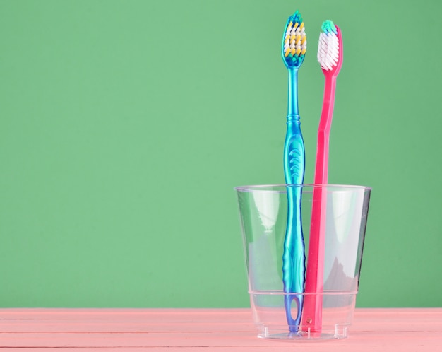 Dos cepillos de dientes en una taza de plástico transparente en el baño.