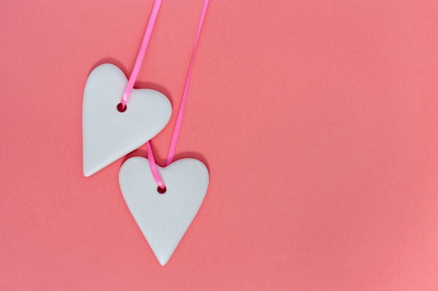 Dos cerámicas corazones de color blanco de cerca en papel rosa