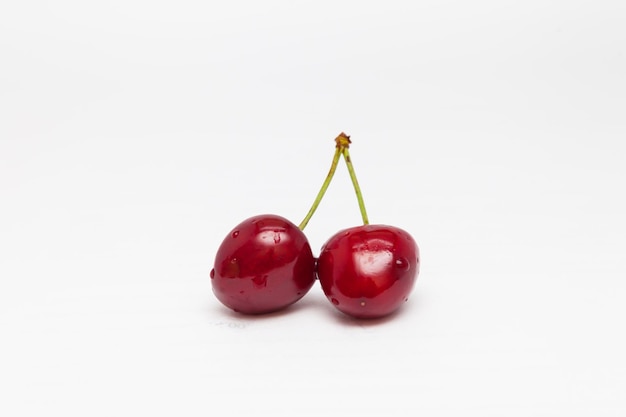 Dos cerezas rojas sobre un fondo blanco.