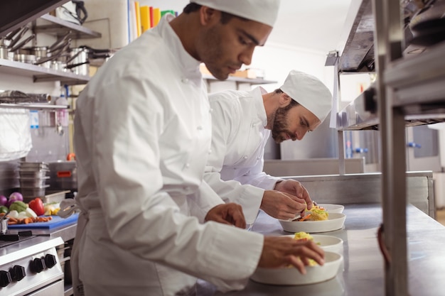 Dos chefs decorando comida en cocina comercial