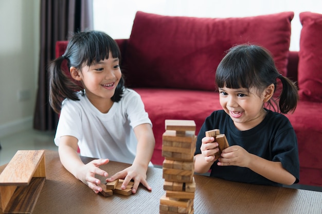 Dos chica asiática jugando pilas de madera en casa