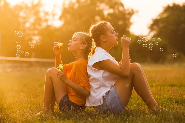 Dos chicas adolescentes se divierten en el parque. Dos amigos al aire libre. Gente de verano haciendo burbujas