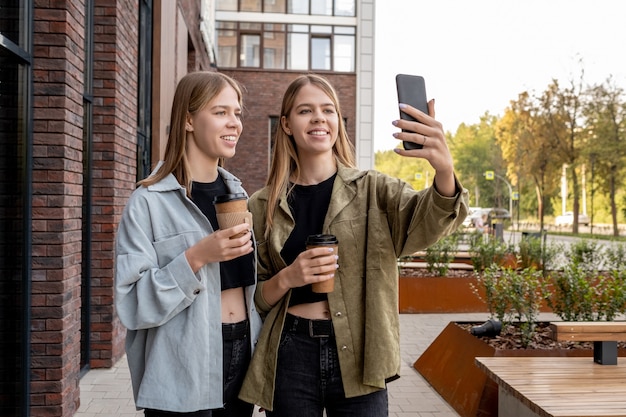 Dos chicas adolescentes rubias lindas haciendo selfie al aire libre