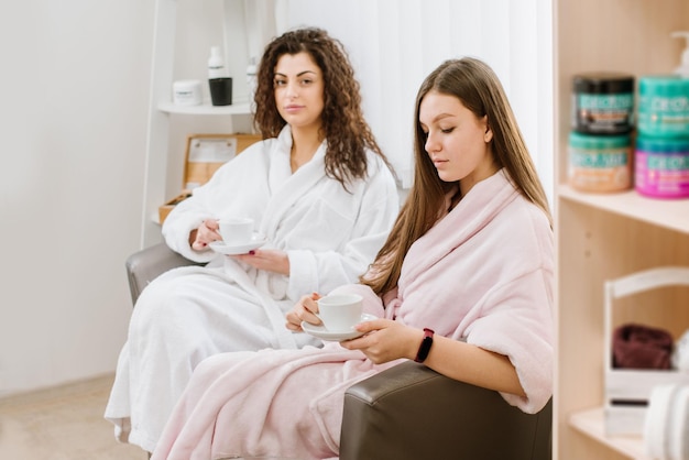 Dos chicas en albornoces esperando en el salón SPA