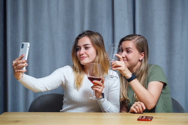 Dos chicas de apariencia europea están sentadas a la mesa con copas de vino. Conversación de novias con bebidas alcohólicas.