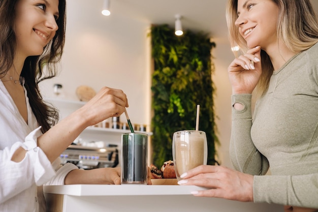 Dos chicas de aspecto deportivo con cócteles en las manos discuten sobre alimentación saludable y dieta