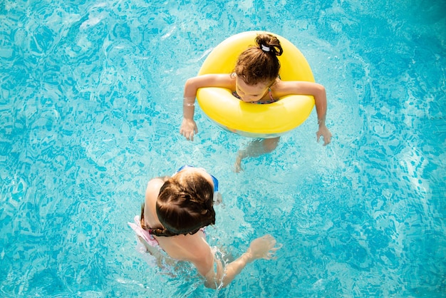 Dos chicas se bañan en la piscina con gafas azules para nadar.