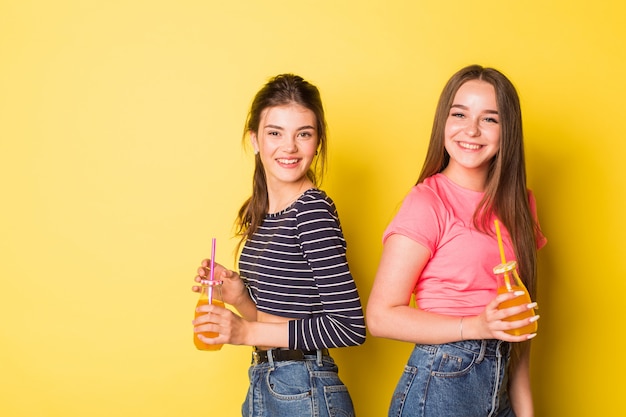 Dos chicas de belleza natural alegre joven inconformista posando juntos en amarillo