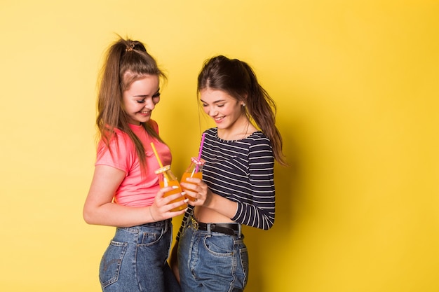 Dos chicas de belleza natural alegre joven inconformista posando juntos en amarillo