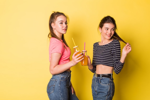 Dos chicas de belleza natural alegre joven inconformista posando juntos en amarillo