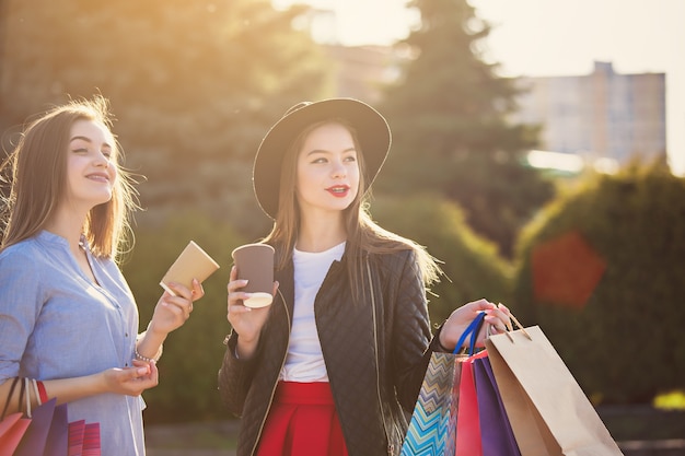 Dos chicas caminando con bolsas de la compra en las calles de la ciudad en un día soleado