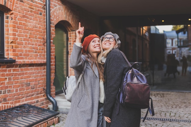 Dos chicas caminando juntas en la calle y tomándose las manos llevan ropa de primavera u otoño