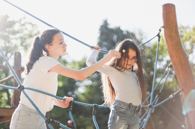 Dos chicas caucásicas, la mayor viste a la más joven con el pelo largo y castaño, una margarita