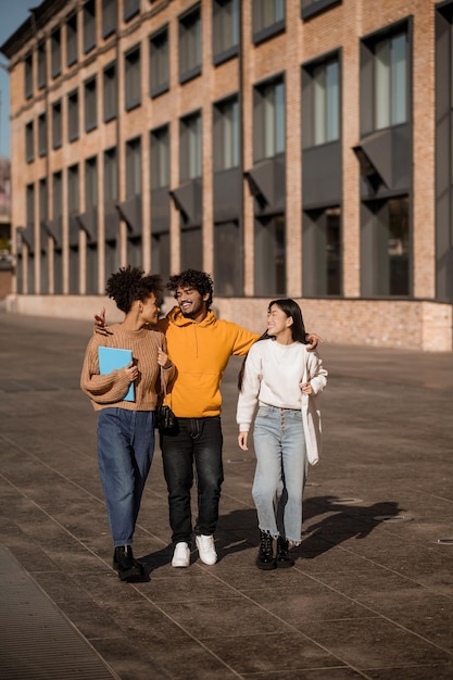 Foto dos chicas y chico hablando caminando por la calle