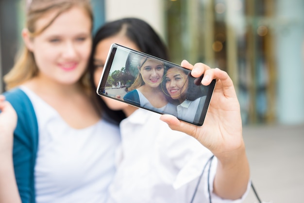 Dos chicas diversas haciendo selfie foto al aire libre