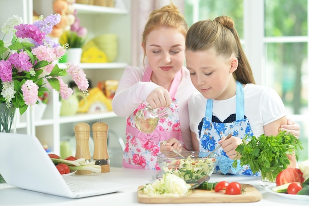 Dos chicas divertidas preparando ensalada fresca