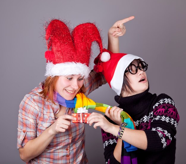 Dos chicas divertidas con regalos de Navidad. Tiro del estudio.