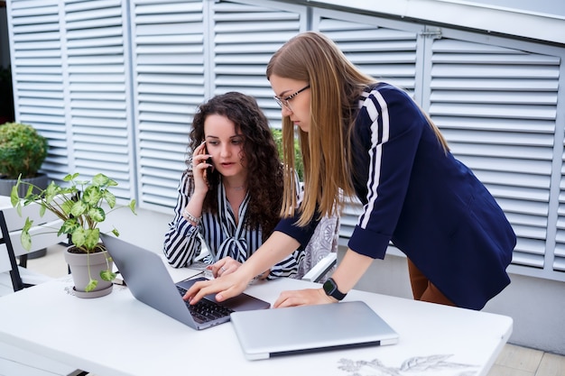 Dos chicas empresarias serias discutiendo un proyecto empresarial, trabajando juntas en la oficina, una consultora seria y un cliente hablando en una reunión, colegas ejecutivos enfocados comparten ideas